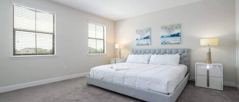 A bedroom with a bed, two bedside tables, a window, and artwork on the wall.