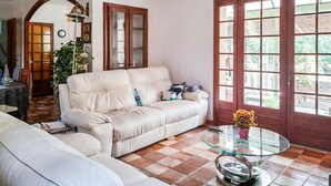 A living room with a beige sofa, a glass coffee table, and a tiled floor. - Maison piscine à Anduze (Anduze)