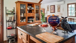 A kitchen with a wooden cabinet, a fruit bowl, and a decorative owl. - Maison piscine à Anduze (Anduze)