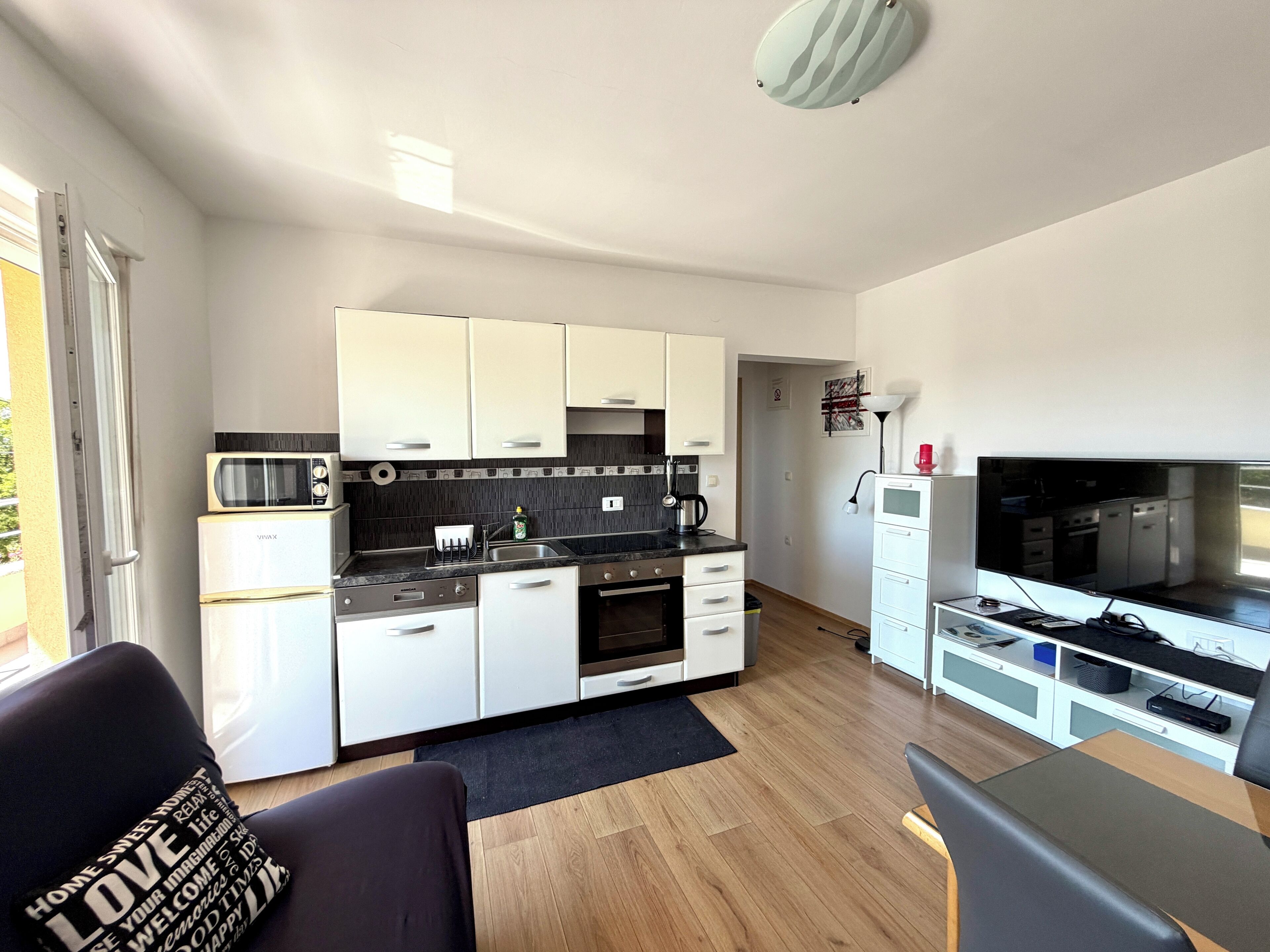 A compact kitchen with white cabinets, a black countertop, and a built-in oven.