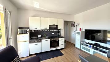 A compact kitchen with white cabinets, a black countertop, and a built-in oven.