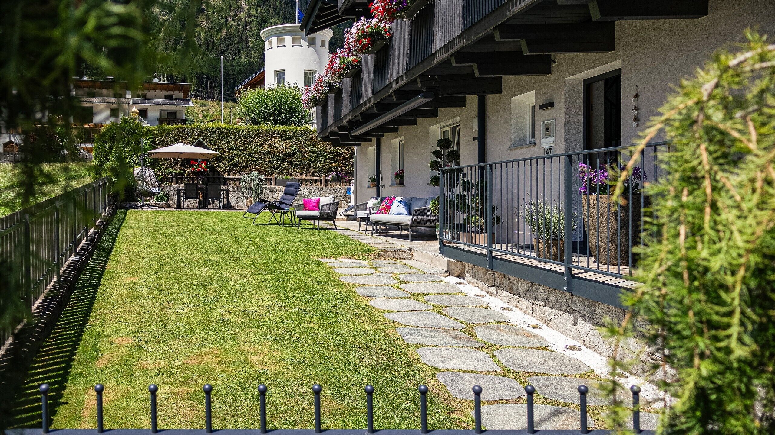 A well-maintained garden with a stone pathway leading to a building with a balcony.