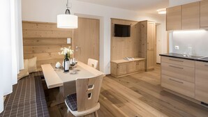 Una cocina moderna con armarios de madera, una mesa de comedor con sillas y un televisor montado en la pared.