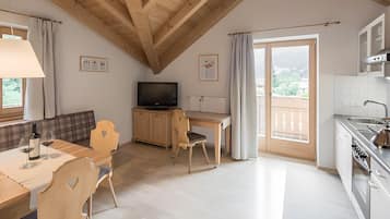 Une cuisine moderne avec un coin repas, des poutres en bois au plafond et une vue dégagée grâce à une porte coulissante.