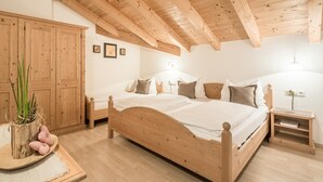 Una cama de madera con cabecera, una mesita de noche, un armario de madera y una planta sobre una mesa.