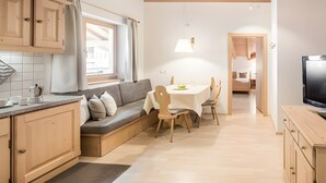 Una cocina moderna con armarios de madera, una zona de comedor con mesa y sillas, un sofá y un televisor.