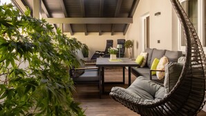 Un área de estar exterior moderna con una mesa de comedor, sillas, un sofá y una sillona colgante.