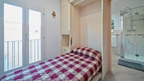 Een slaapkamer met een bed, een kledingkast en een douchehoek.