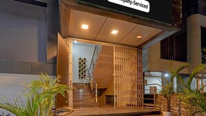 A hotel entrance with a staircase, a company-serviced sign, and potted plants. - Premiumsri Sai Suites (Bengaluru)