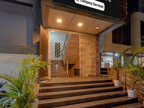 A hotel entrance with a staircase, a company-serviced sign, and potted plants. - Premiumsri Sai Suites (Bengaluru)