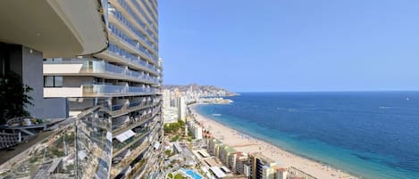 A high-rise hotel with a pool, beach view, and multiple balconies.