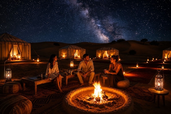 Un campamento en el desierto con yurtas, un hogar central y un cielo estrellado.