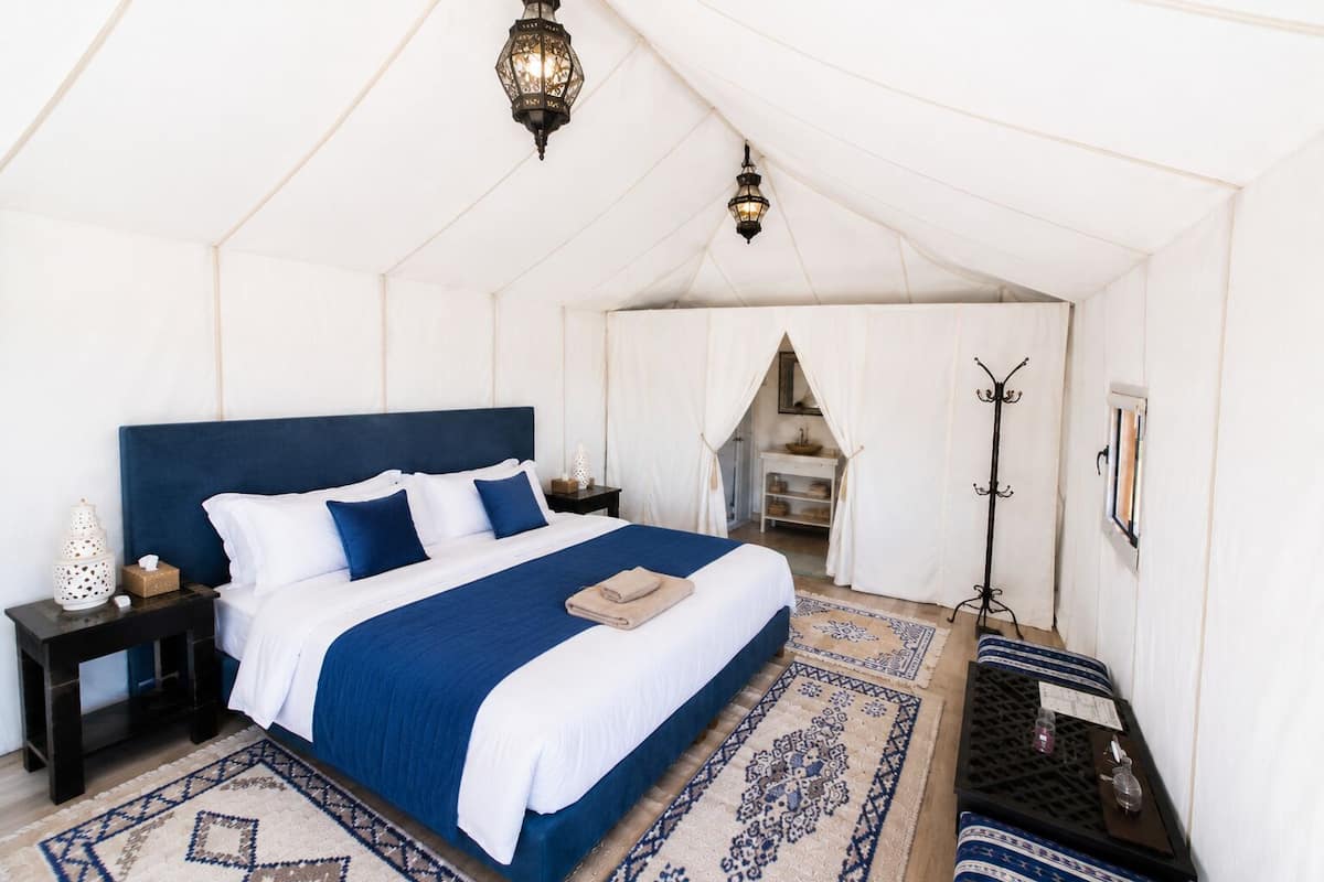 Una habitación con carpa que incluye una cama, mesitas de noche, una lámpara y un armario.