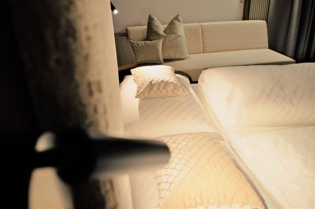 A hotel room with a bed, a sofa, and a nightstand with a lamp.