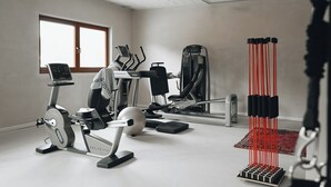 Un gimnasio con diversos equipos de ejercicio, incluyendo cintas de correr, una elíptica y una máquina de remo.