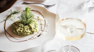 A plate of risotto garnished with herbs, a glass of white wine, and a folded napkin on a table.