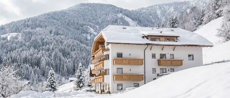 Un hôtel à plusieurs étages, doté de balcons, situé dans un cadre montagneux enneigé.