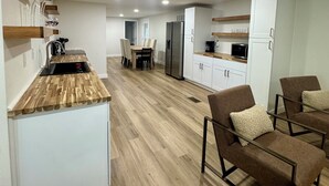 A modern kitchen with wooden countertops, white cabinets, and a dining area with chairs. - Lake Texoma Haven-Luxury Getaway Near Lake Texoma w/ Hot Tub (Pottsboro)
