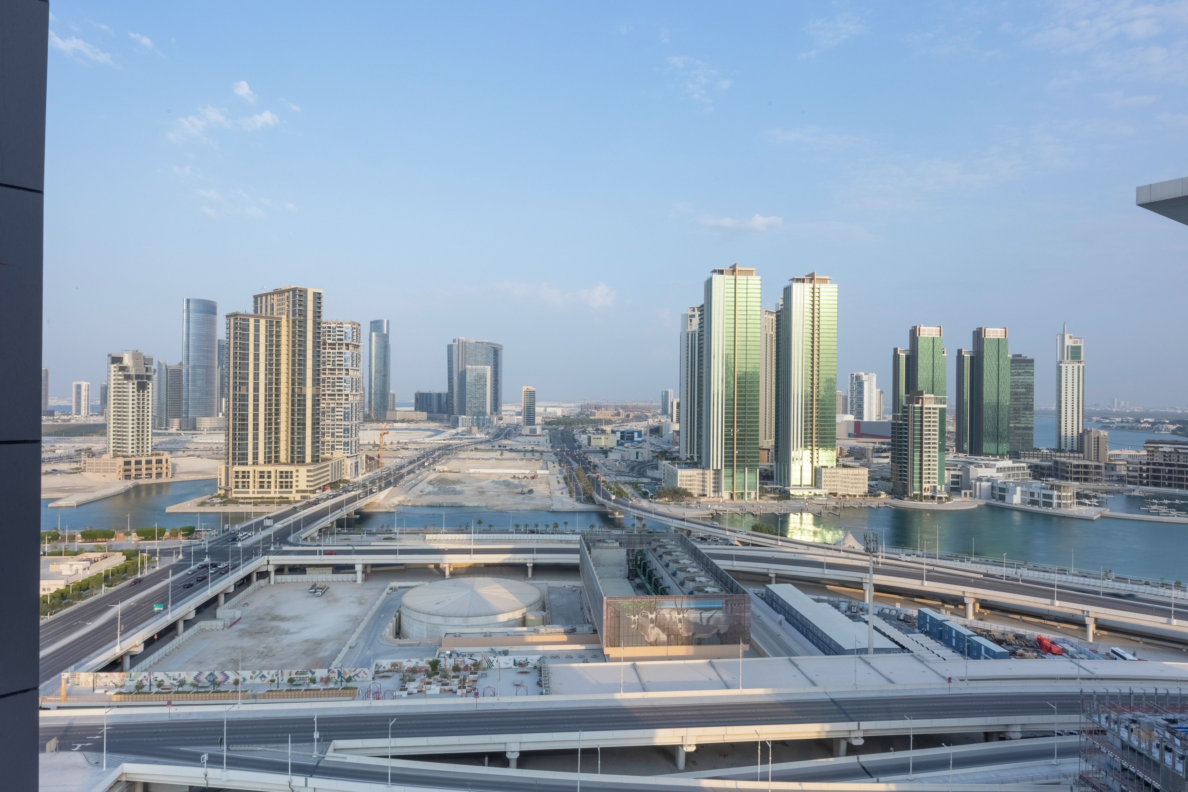 A cityscape with modern high-rise buildings, a river, and a highway.