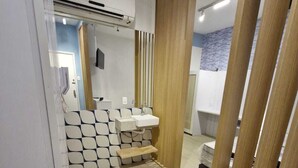Un baño moderno con lavamanos empotrado, un espejo y una división de madera.