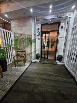 A hotel entrance with a bench, potted plants, and a tiled floor leading to a door. - Adorável Studio Copacabana (Rio de Janeiro)