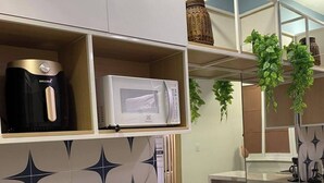 Una cocina equipada con microondas, cafetera y placa de inducción.