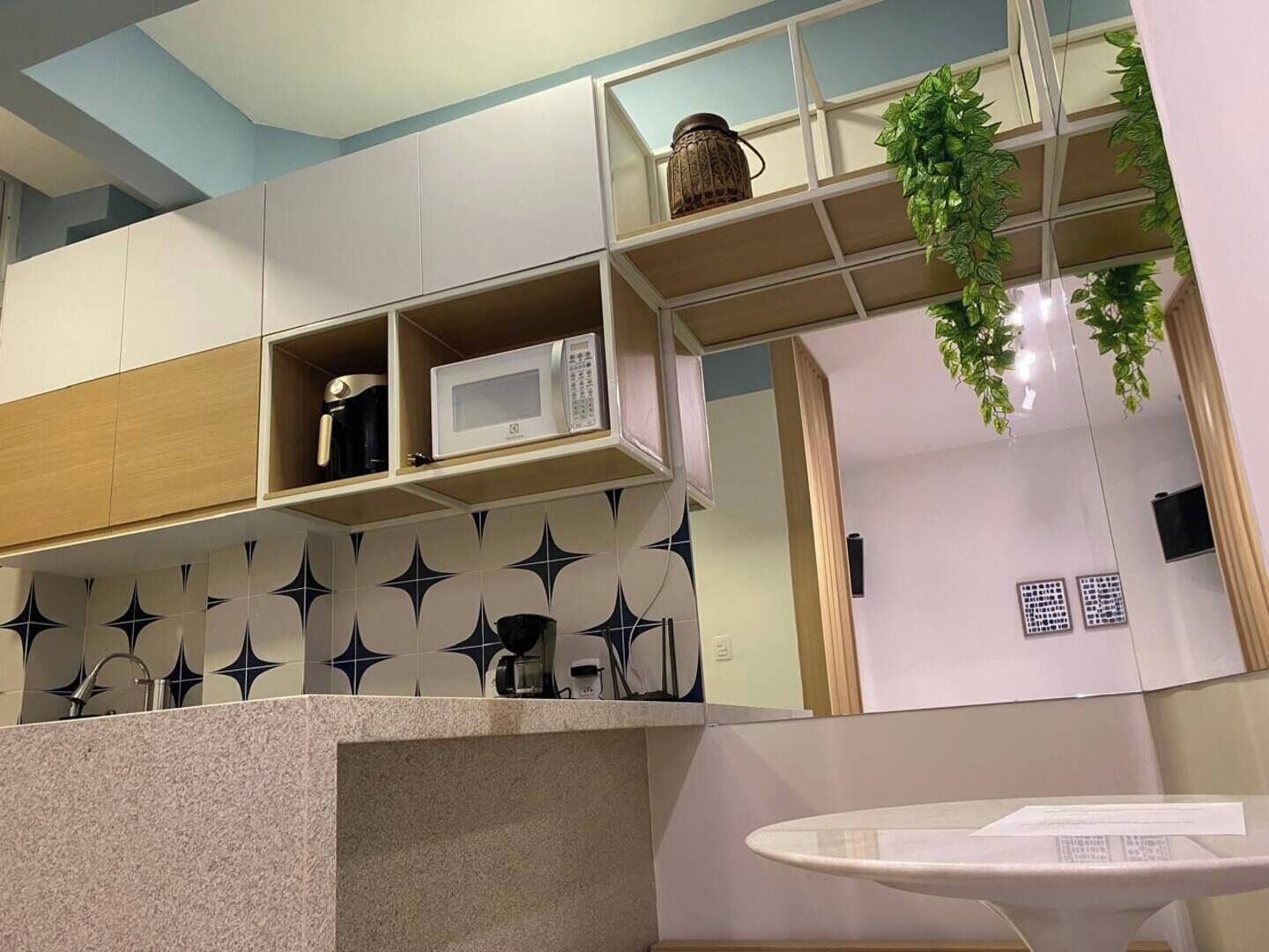 Una cocina moderna con microondas, una planta colgante y un salpicadero con diseño.