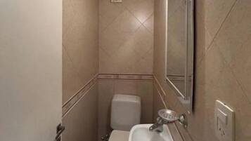 Un baño pequeño con inodoro, lavamanos y espejo.