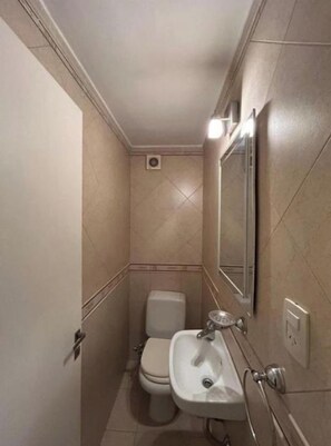 Un baño pequeño con inodoro, lavamanos y espejo.