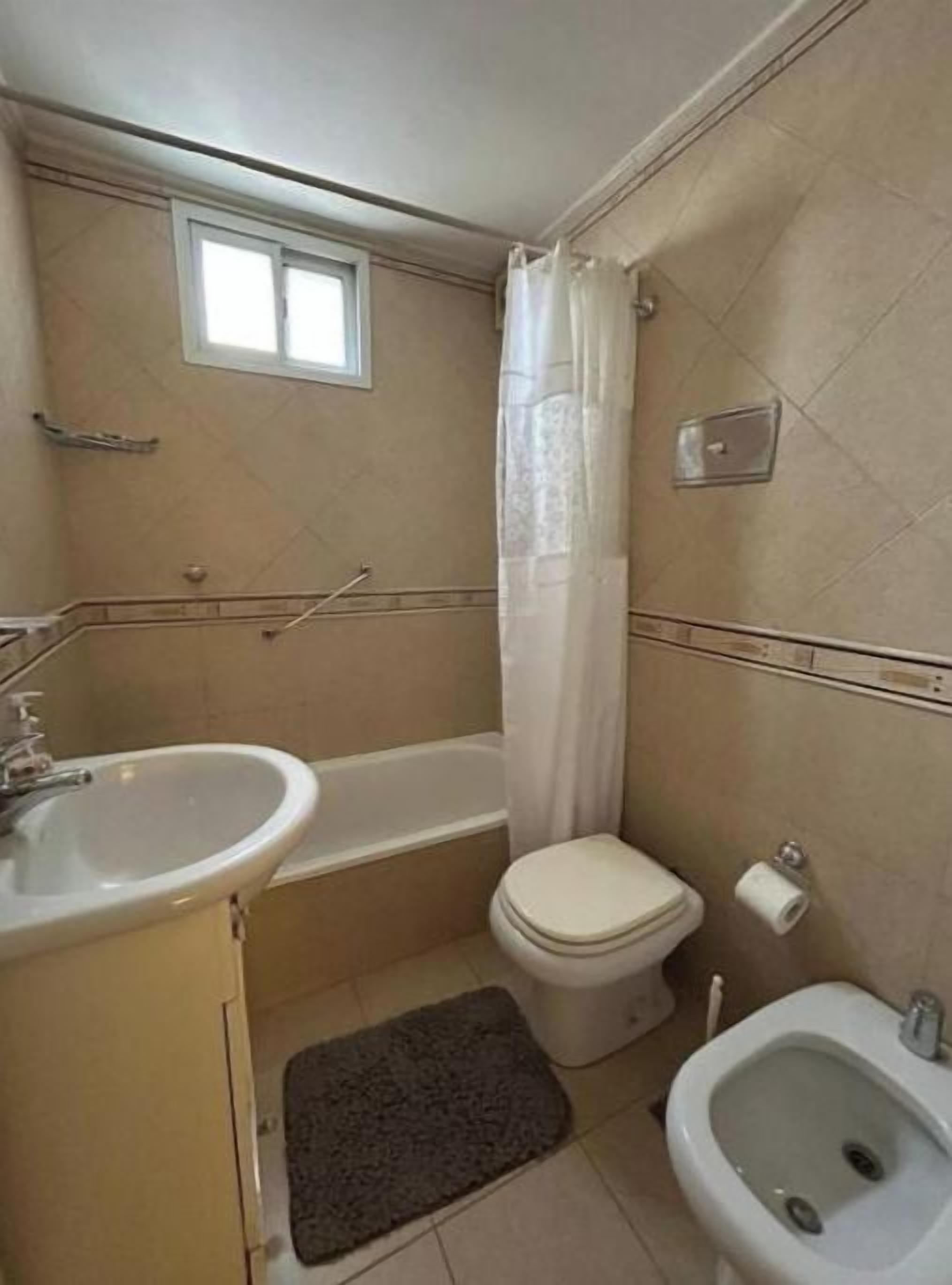 A small bathroom with a bathtub, toilet, sink, and bidet.