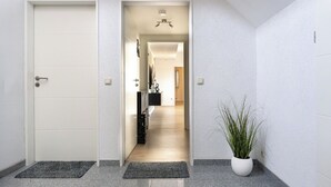 Ein Flur mit einer weißen Tür, einem Blumentopf und einer Lampe.