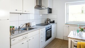 Eine moderne Küche mit weißen Schränken, einem eingebauten Backofen, einer Mikrowelle und einem Fenster mit Blick.