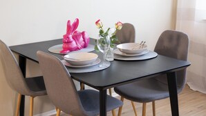 Ein Esstisch mit vier Stühlen, einer Blumenvase und einer rosa Hasenfigur.