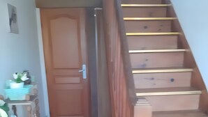 Ein Flur mit einer Holztreppe, einer Tür und einem Tresen mit Gegenständen darauf.