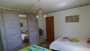Ein Schlafzimmer mit zwei Betten, einem Kleiderschrank, einem Spiegel, einem Deckenventilator und einem an der Wand hängenden Bild.