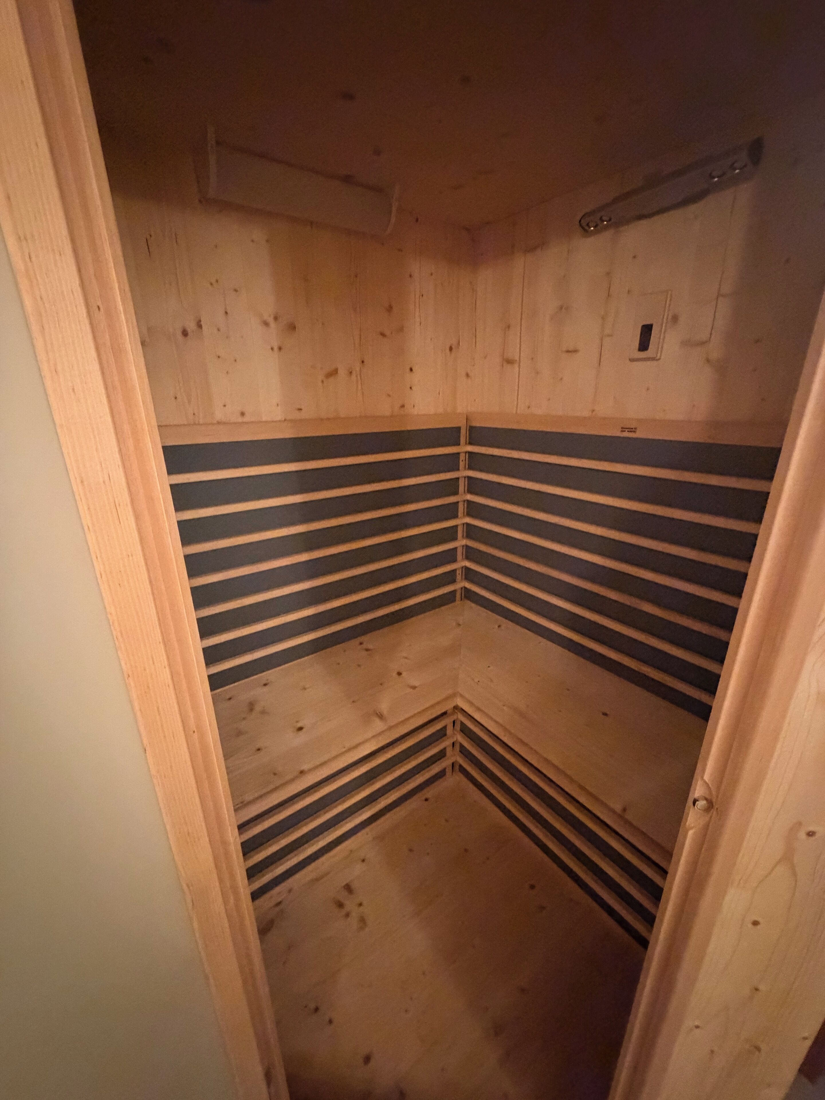 Un sauna en bois avec un plafond incliné et un banc.