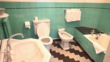 A bathroom with a sink, toilet, bidet, and bathtub.