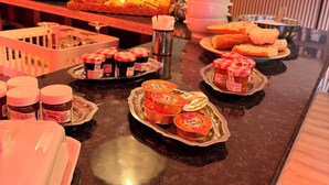 A buffet with various food items, including pastries and condiments, arranged on a counter. - HOTEL DE PARIS  (Poligny)