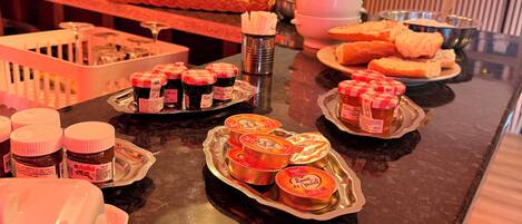 A buffet with various food items, including pastries and condiments, arranged on a counter.