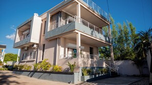 A multi-story residential building with balconies, a satellite dish, and a small garden area.