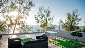 A rooftop patio with outdoor furniture, a view of the sea, and a railing.
