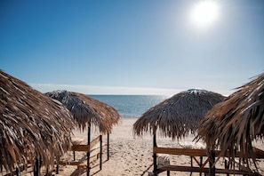 A beach with thatched umbrellas and wooden benches.