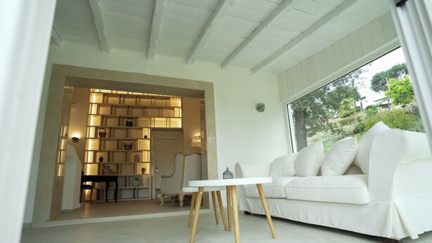 A modern interior with a white sofa, a table, and a built-in shelving unit with warm lighting.