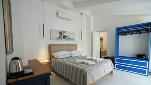 A hotel room with a bed, bedside table, and a wardrobe with hanging clothes.
