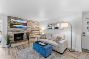A living room with a fireplace, a sofa, a coffee table, and a TV mounted on the wall. - Downtown Breckenridge Retreat at Edelweiss (Breckenridge)