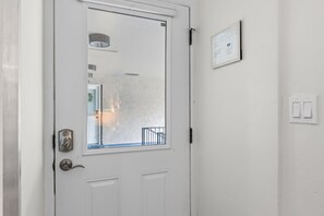A white door with a window, a wall-mounted light switch, and a framed document on the wall. - Downtown Breckenridge Retreat at Edelweiss (Breckenridge)