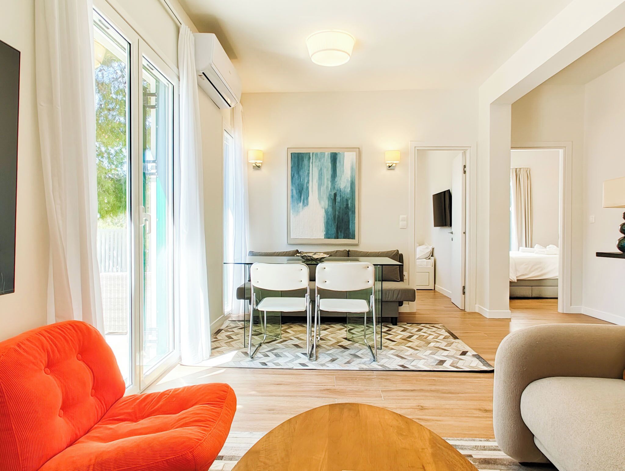 Una sala moderna con un sofá, un comedor con sillas, un cuadro y un televisor.