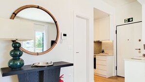 A modern kitchen with white cabinets, a wooden countertop, and a round mirror. - Colorful Riviera Living in Voula Center (Voula)
