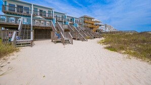 A beachfront hotel with multiple balconies, wooden staircases, and a sandy beach. - Cinco Brisas 2 3 Bedroom Home (Orange Beach)