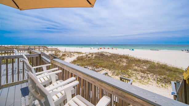 A beach view from a wooden deck with beach chairs and a large umbrella. - Cinco Brisas 2 3 Bedroom Home (Orange Beach)